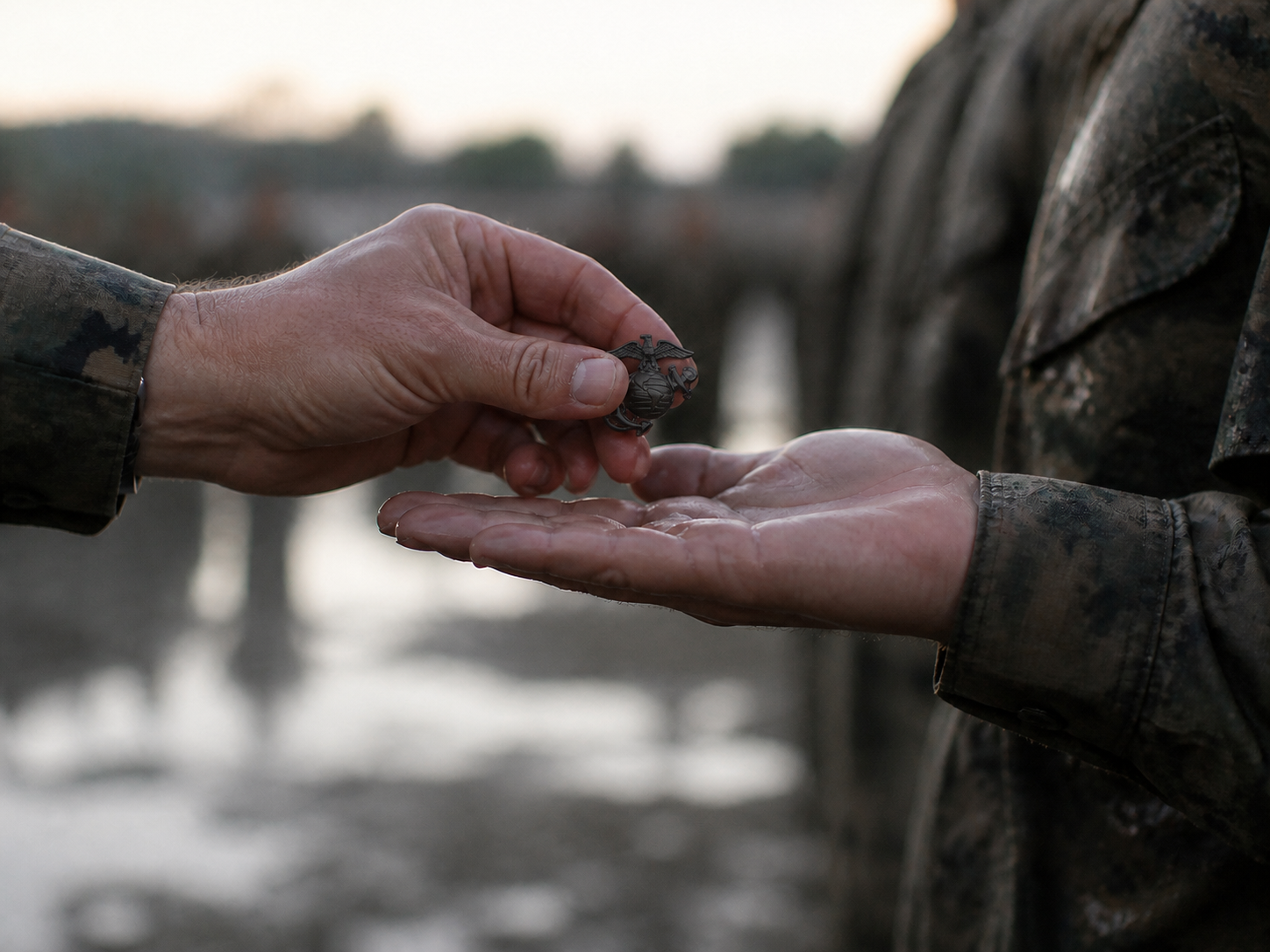 Illustrative recreation of a black Eagle, Globe, and Anchor emblem being presented into a Marine recruit's open hand after the Crucible