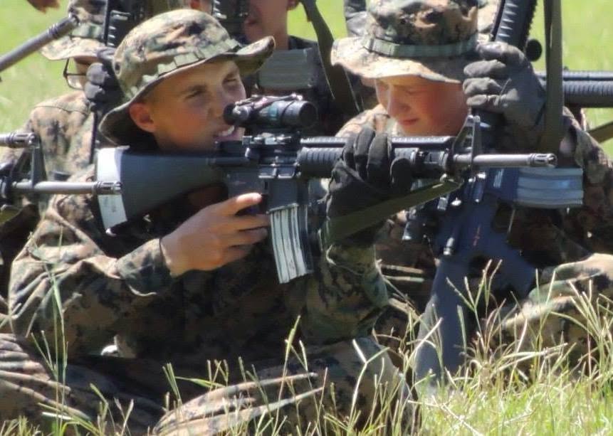 Devyn Harrington in camouflage utility uniform training in a supported firing position on the rifle range