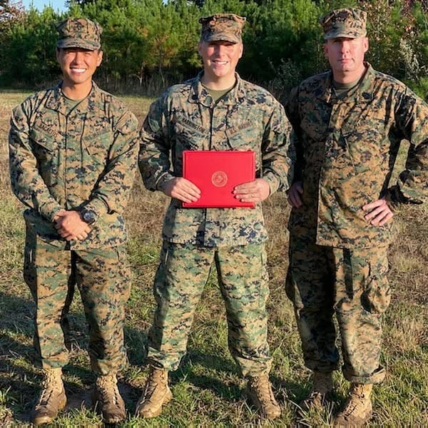 Devyn Harrington holding his Staff Sergeant promotion warrant alongside his communications officer and communications chief during MEFEX at Fort A.P. Hill